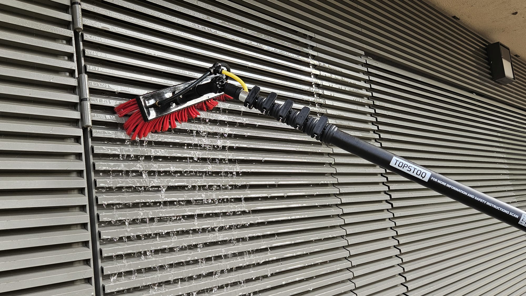 Ervaren glazenwasser maakt ramen en gevels schoon met een Topstoq carbon telescoopsteel, lichtgewicht en stabiel voor professioneel gebruik.