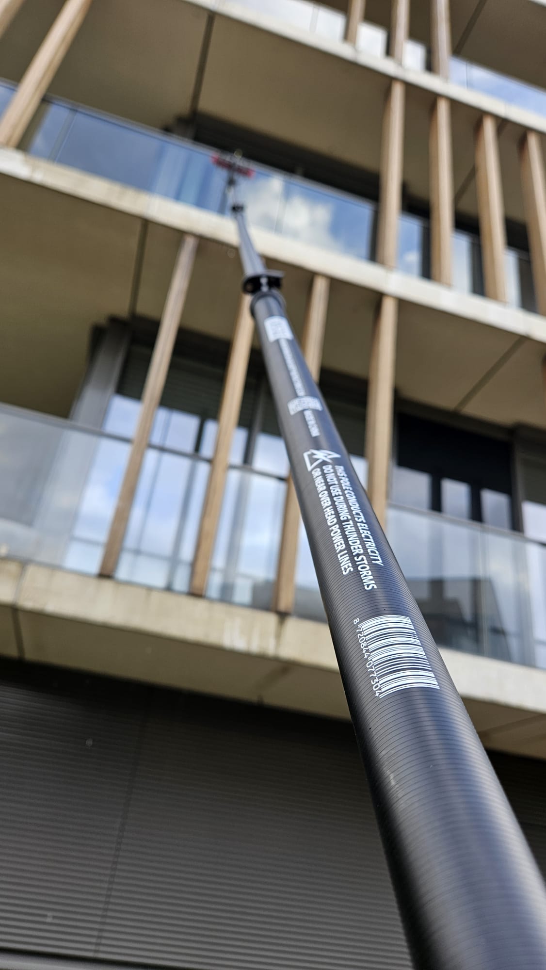 Professionele glazenwasser reinigt ramen en gevels met de Topstoq carbon telescoopsteel van 6,5 meter. Perfect voor tuckeren, gevelreiniging en streeploos werken op hoogte dankzij het lichte en stabiele carbon ontwerp.