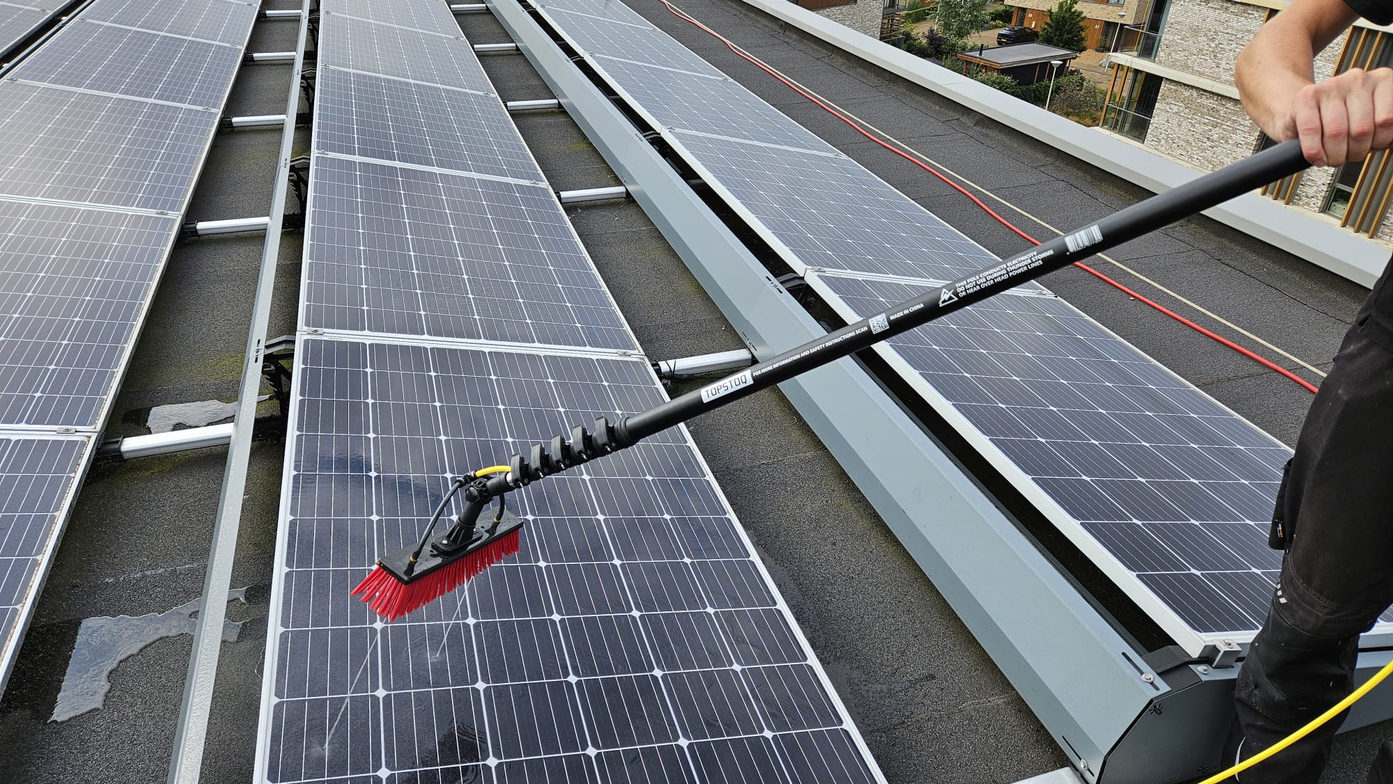 Blije klant van Topstoq poseert buiten met een Topstoq carbon telescoopsteel, trots lachend terwijl hij de lichte en stevige stok laat zien, geschikt voor professioneel glazenwassen en reinigen zonnepanelen.