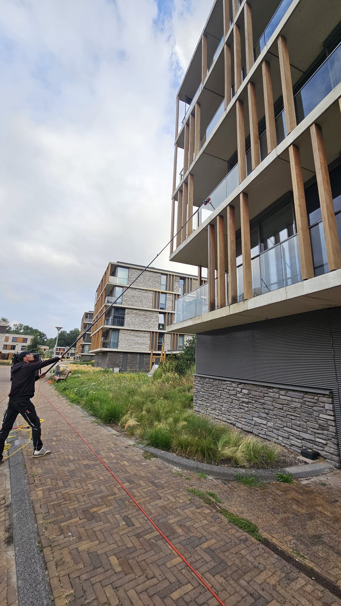 Professionele glazenwasser werkt op 6,5 meter hoogte met de Topstoq carbon telescoopsteel. Lichtgewicht en stabiel voor veilig en efficiënt ramen wassen op grote hoogtes.