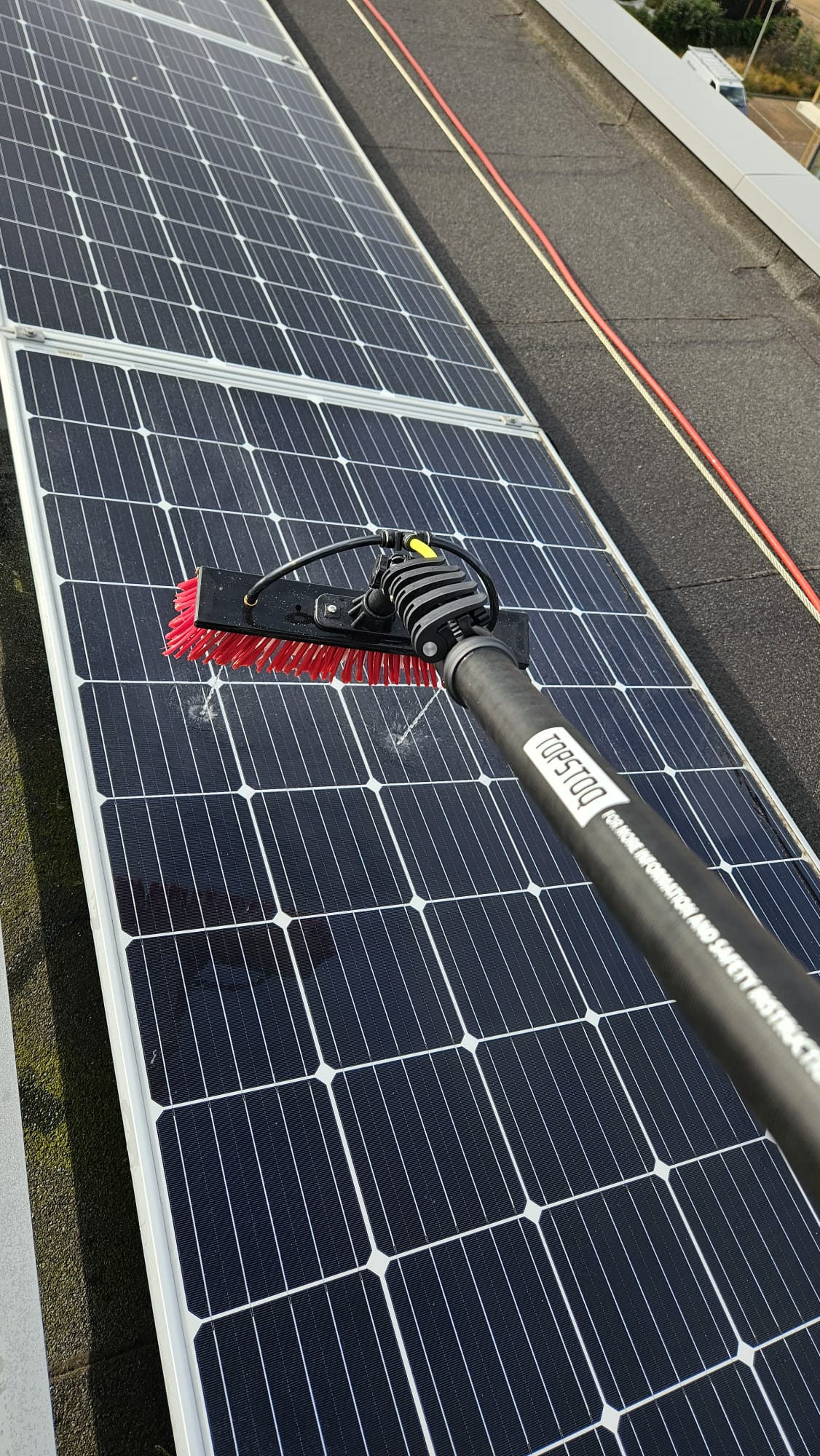 Reinigen van zonnepanelen met de Topstoq carbon telescoopsteel en waterdoorvoerborstel. Lichtgewicht en stabiel voor efficiënt en streeploos schoonmaken van PV-panelen.