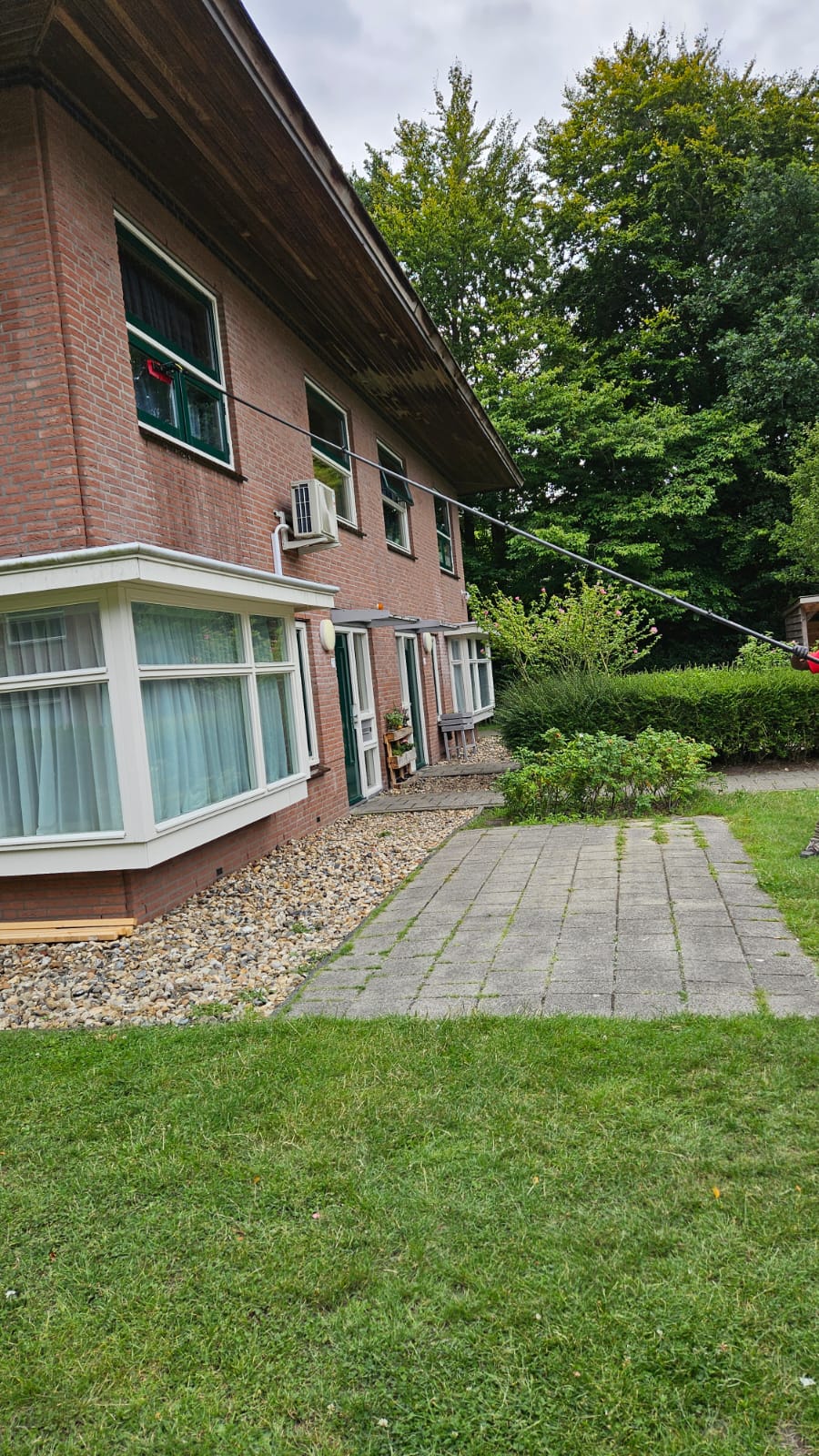 Professionele glazenwasser wast ramen op de eerste verdieping met de Topstoq carbon telescoopsteel van 6,5 meter. Lichtgewicht, stabiel en ideaal voor langdurig werken op hoogte.