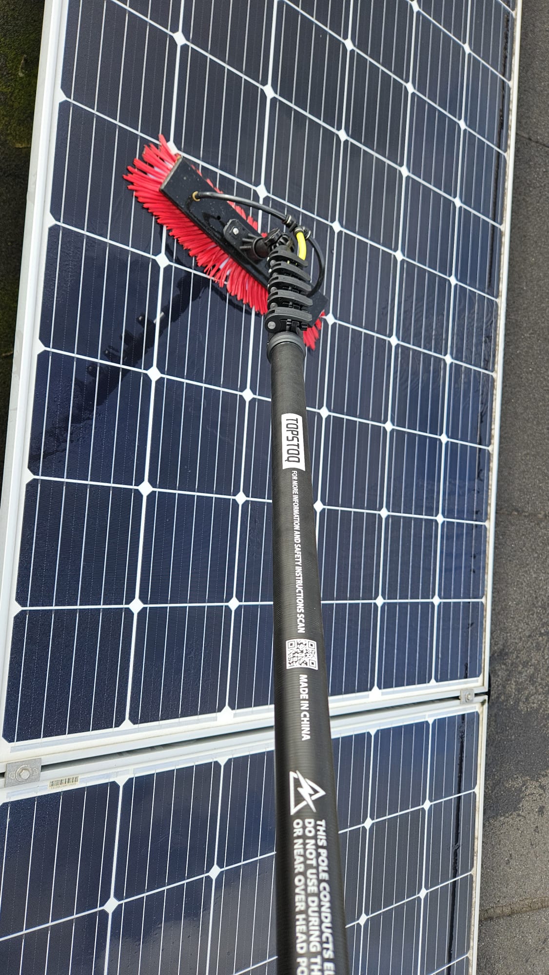 Close-up van de Topstoq carbon telescoopsteel met professionele 
waterdoorvoerborstel tijdens het reinigen van zonnepanelen. Lichtgewicht, stabiel en ideaal voor professioneel onderhoud van PV-panelen.